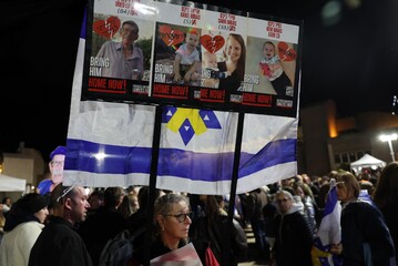 People carry a placard bearing the pictures of Oded Lifshitz and members of the Bibas family