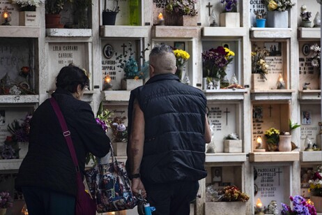 Visitatori portano fiori sulle tombe dei propri cari