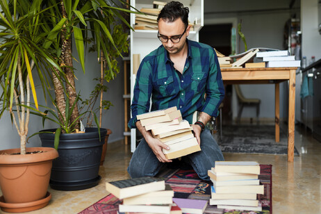 Un uomo mette a posto la libreria foto iStock.