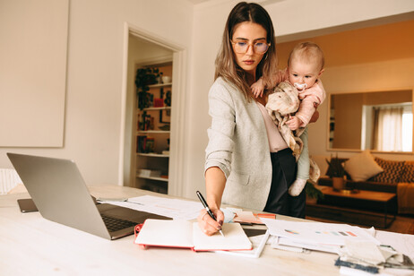 Una mamma lavora e tiene in braccio il suo bambino foto iStock.