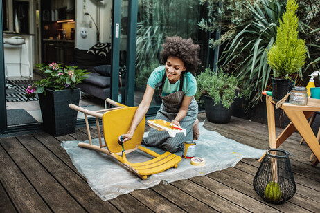 Una donna dipinge una sedia foto iStock.