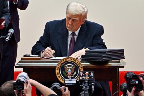 Il presidente Donald Trump mentre firma decine di ordini esecutivi