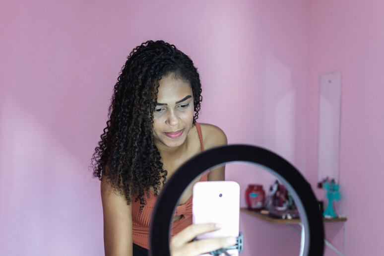 Black young woman filming herself dancing at home to share on social media - RIPRODUZIONE RISERVATA